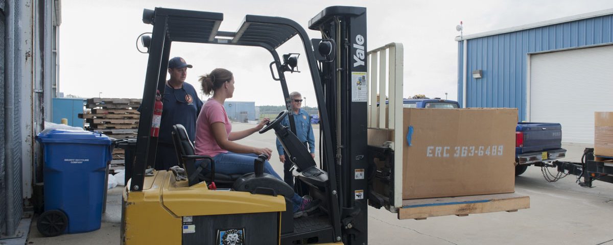 District staff driving a fork lift at district headquarters