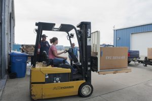 District staff driving a fork lift at district headquarters
