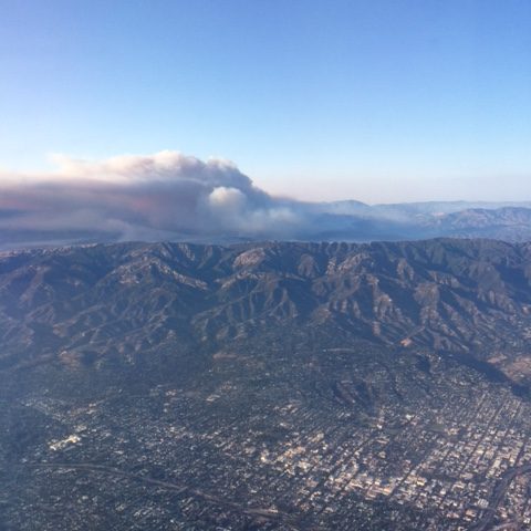 Aerial photo of mountain range with smoke plume in the background