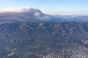 Aerial photo of mountain range with smoke plume in the background