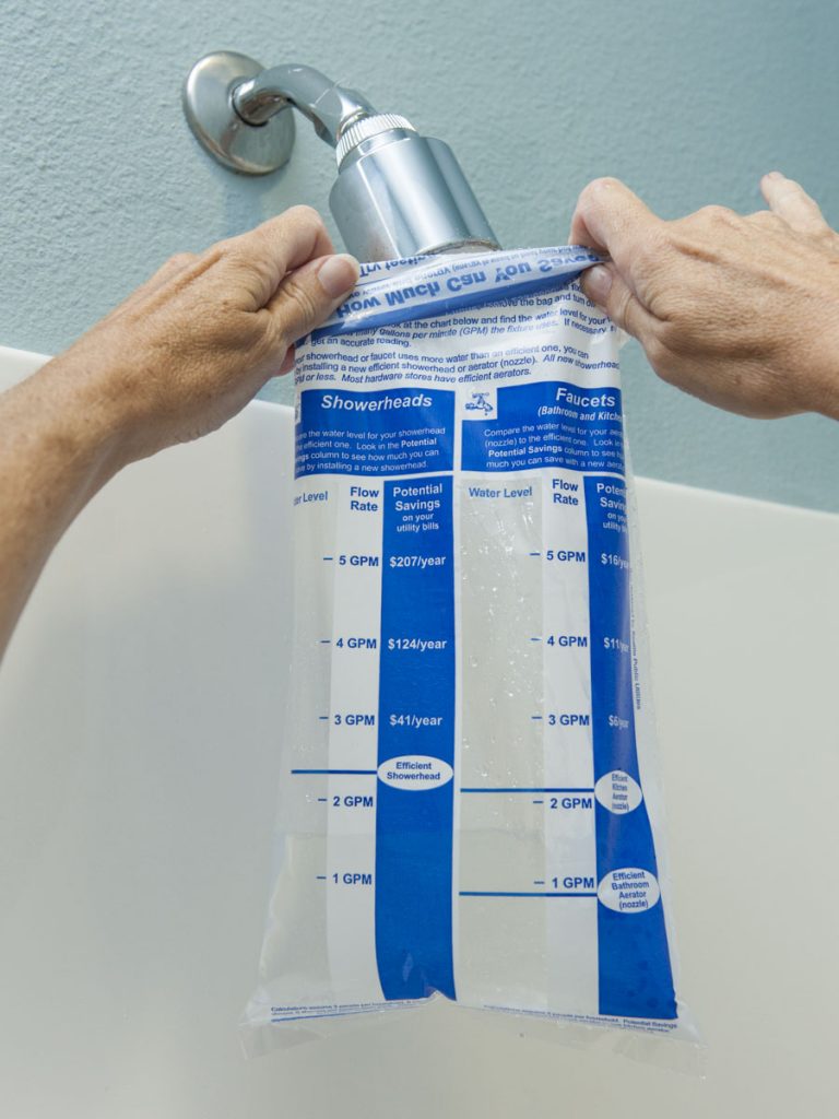 Measuring shower water flow Person measuring shower water flow with a marked bag