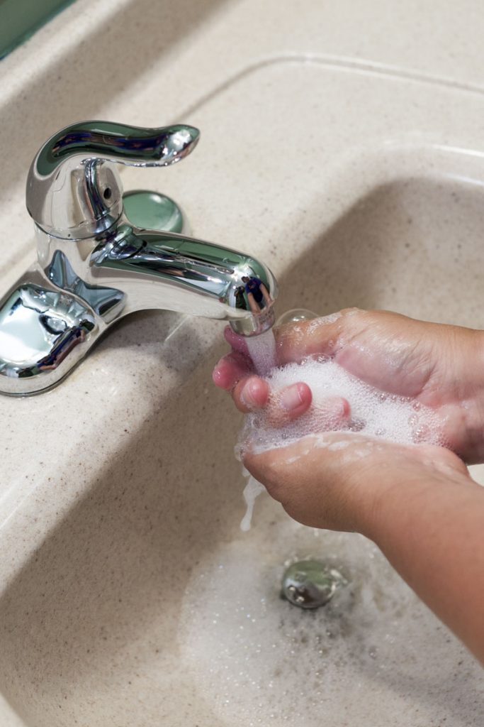 Washing hands in bathroom sink Person washing their hands in bathroom sink