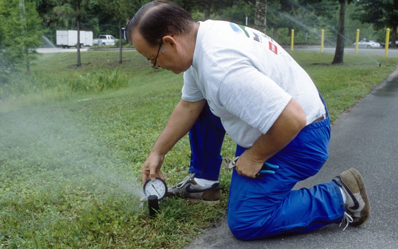 Man measuring the water pressure at an irrigation spray head