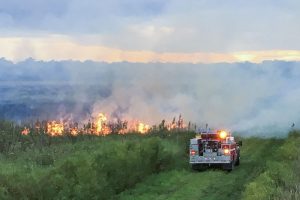 Fire truck next to a fire buring in an open area