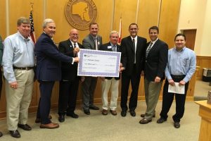 Jim Troiano and Putnam County commissioners and staff with a cost-share check at a commission meeting