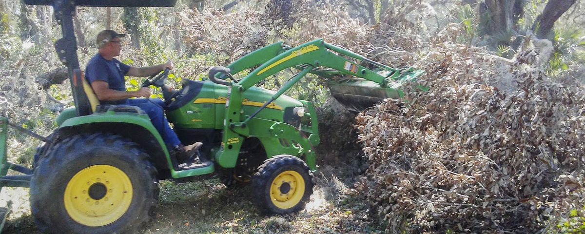 District staff using a frontloader to move tree debris