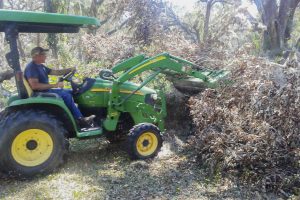 District staff using a frontloader to move tree debris