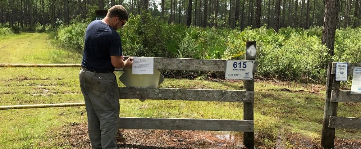 District staff putting up property closure notice on entrance to conservation area