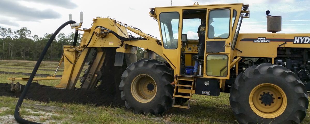 Large trenching tractor installing sub-irrigation drain tiles in a farm