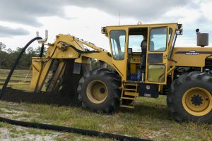 Large trenching tractor installing sub-irrigation drain tiles in a farm