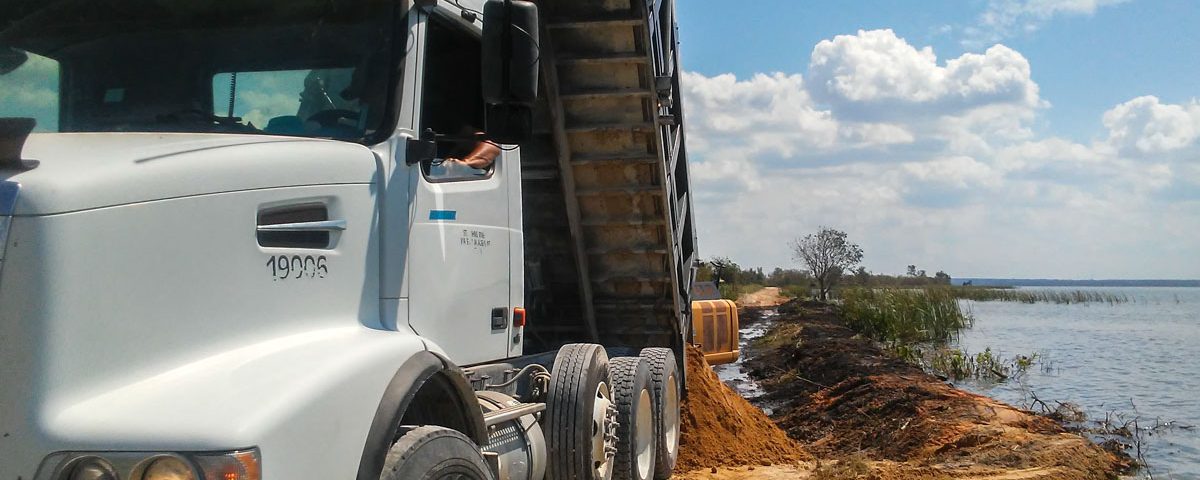 Dump truck delilvering fill material to a levee on Lake Apopka's north shore
