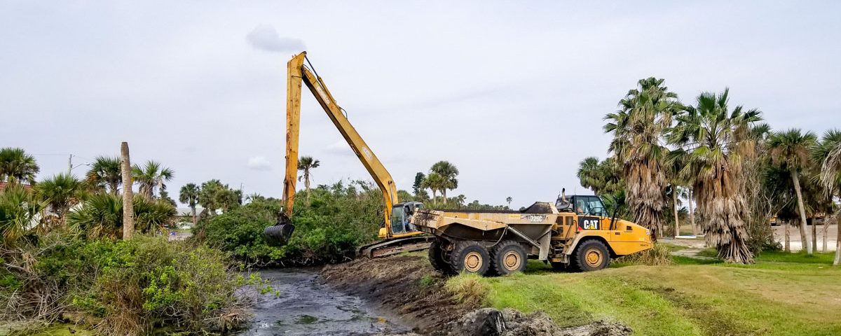 Backhoe expanding a stomwwater containment area on a golf course