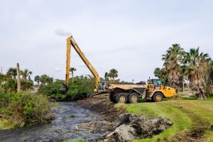 Backhoe expanding a stomwwater containment area on a golf course