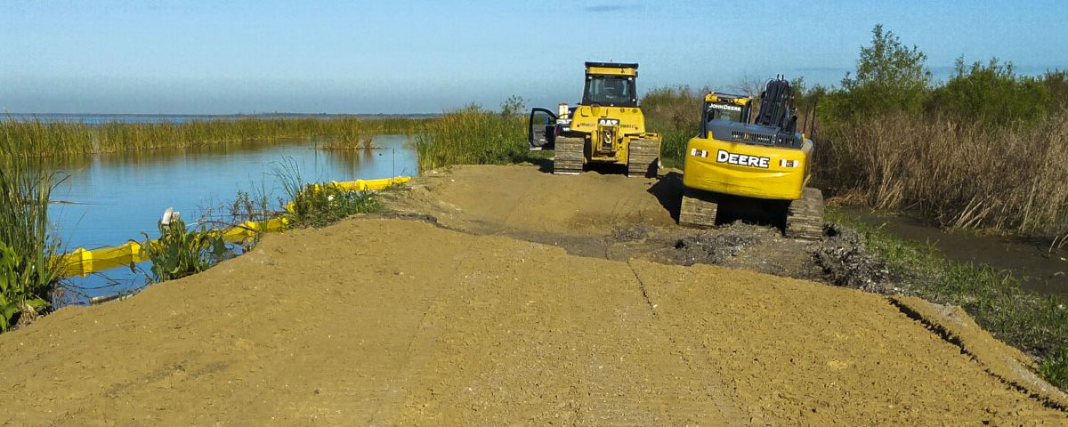 Tractors working to stabilize a levee along Lake Apopka