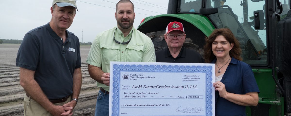 District staff presenting cost-share check to farmers at thier farm