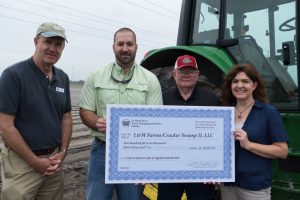 District staff presenting cost-share check to farmers at thier farm