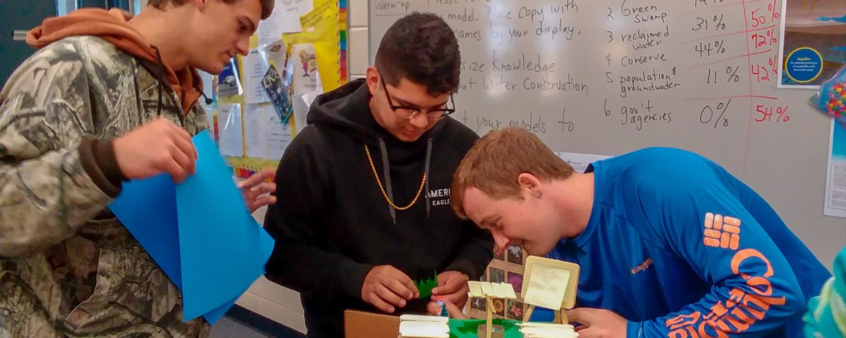 High school students in a classroom working on a model