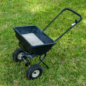 Lawn fertilizer spreader sitting on grass