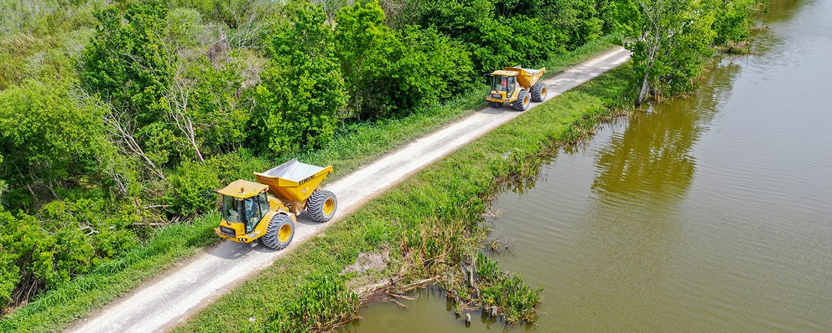 Dump trucks driving on a levee along Lake Apopka