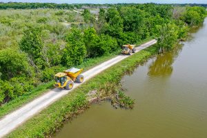 Dump trucks driving on a levee along Lake Apopka