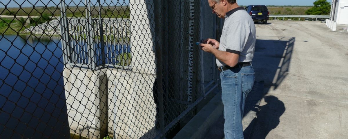John Richmond using his cell phone to test a water control structure