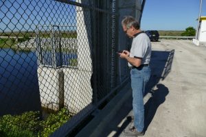 John Richmond using his cell phone to test a water control structure