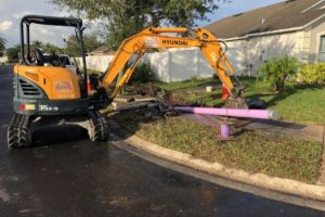 Excavator laying down purple pipes