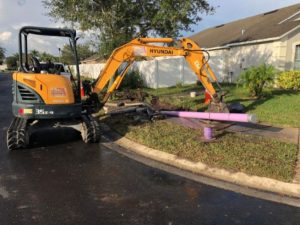 Excavator laying down purple pipes