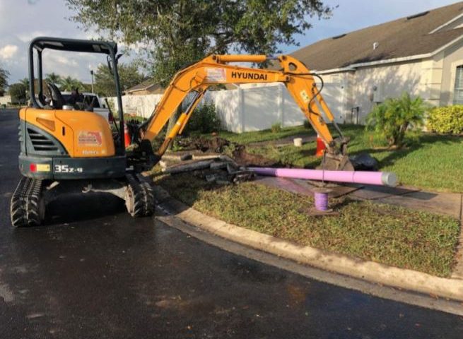 Excavator laying down purple pipes