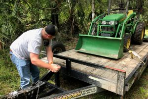 District staff member unloads a tractor from a trailer