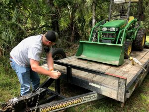 District staff member unloads a tractor from a trailer