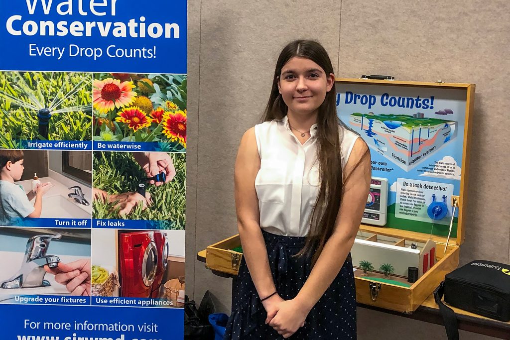 Madison Aprandini standing with a water conservation display