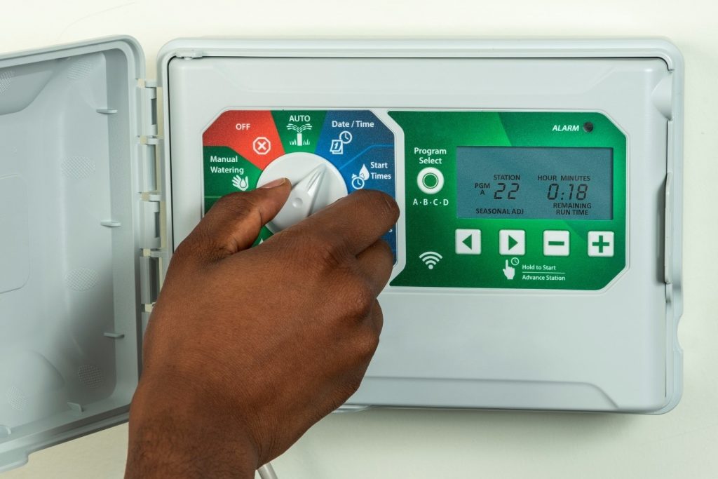 Person's hand adjusting a sprinkler system