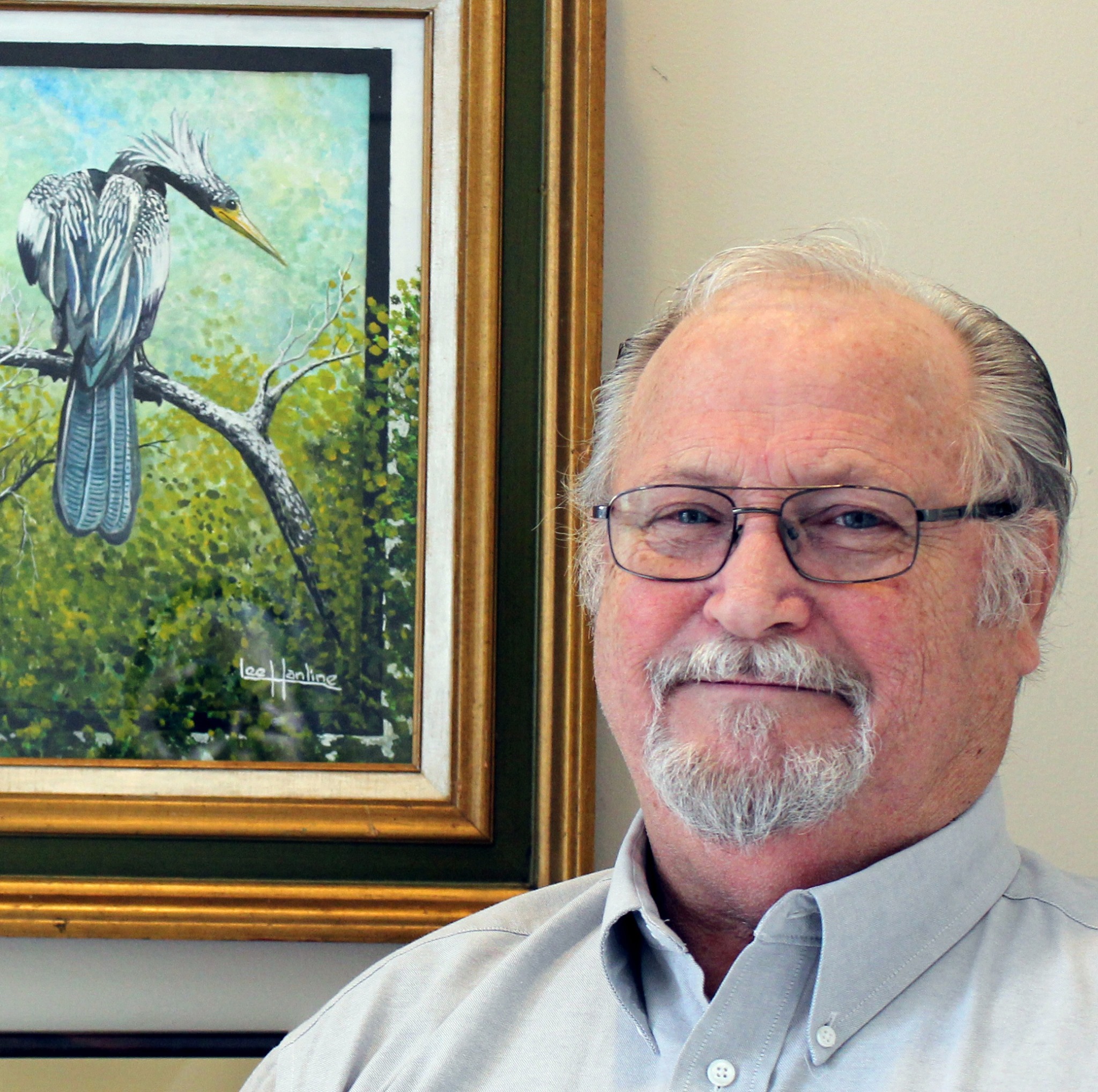 Lee Hanline next to one of his wildlife paintings of a heron