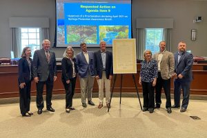 Board members and Dr, Shortelle standing around a tripod holding a proclamation