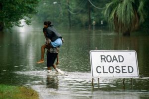 A person carying someone through highwaters