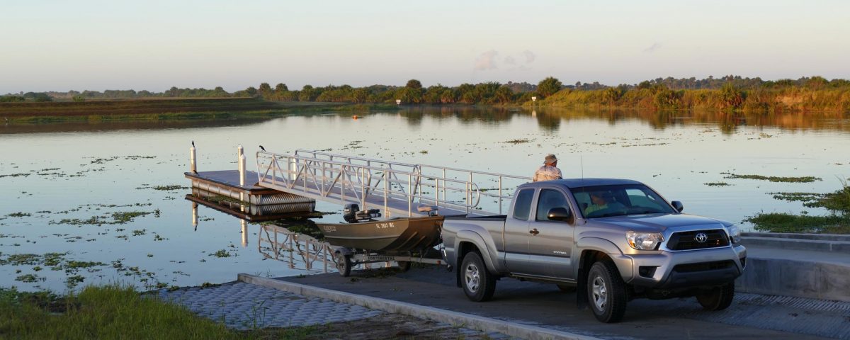 Man using a Toyota truck to load a small pontoon boat