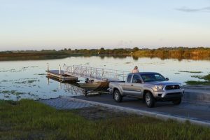 Man using a Toyota truck to load a small pontoon boat