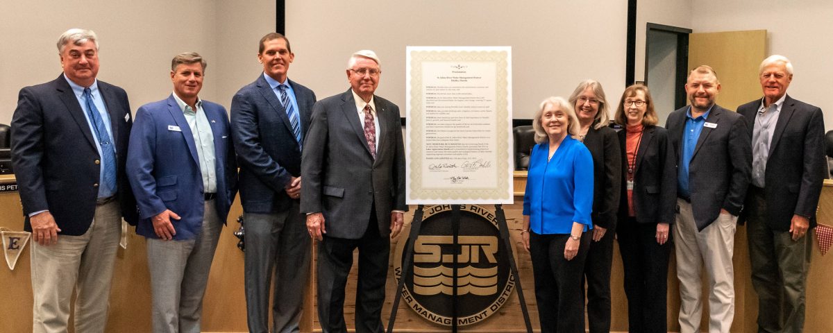 Disctict board members posing next to a plaque