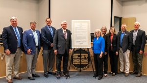 Disctict board members posing next to a plaque