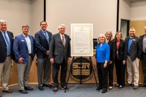 Disctict board members posing next to a plaque