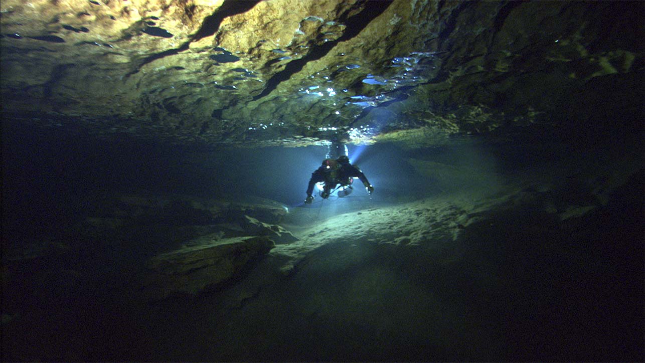 A single diver swimming in a cave