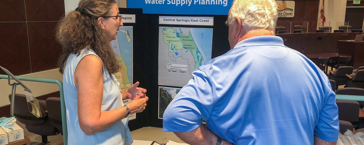 Two people talking in front of a display about water supply planning