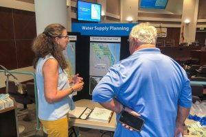 Two people talking in front of a display about water supply planning