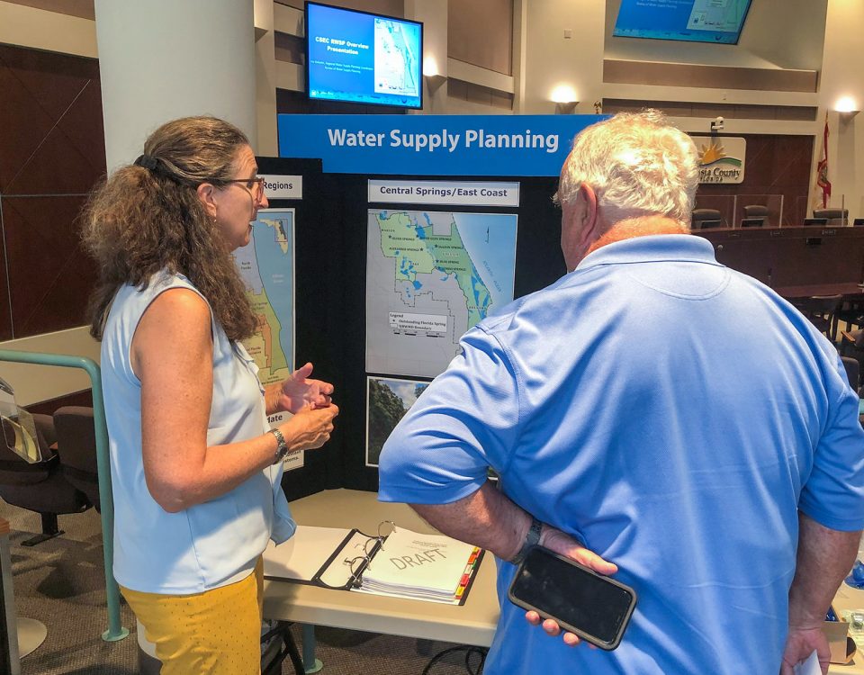 Two people talking in front of a display about water supply planning