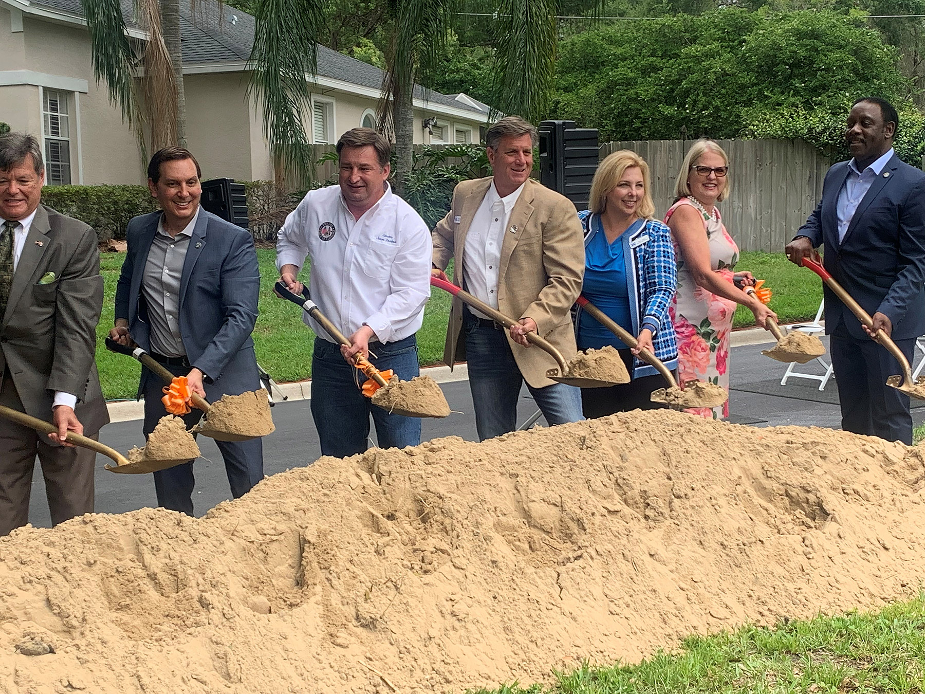 People with shovels standing behind a pile of sand