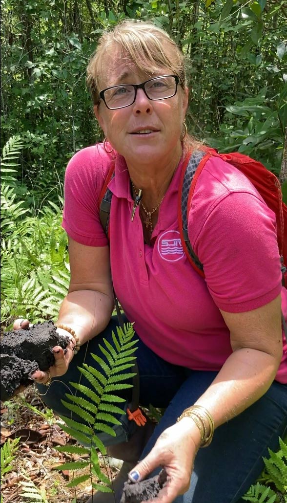 Christine Wentze kneeling next to a fern