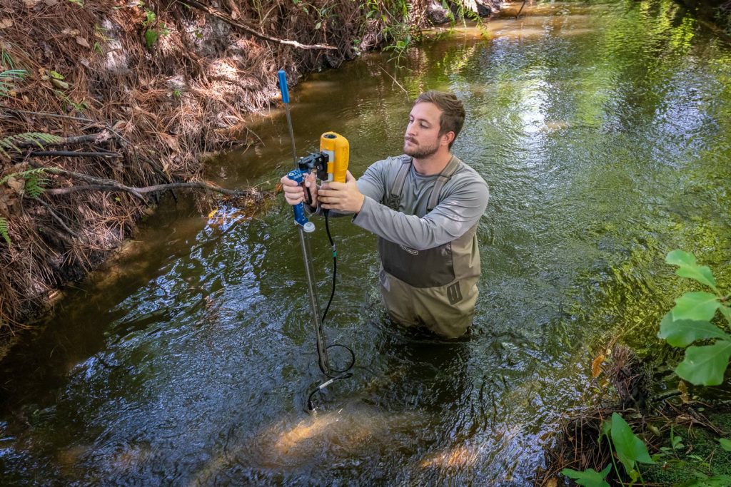 monitoring Man standing waist-deep on a creek