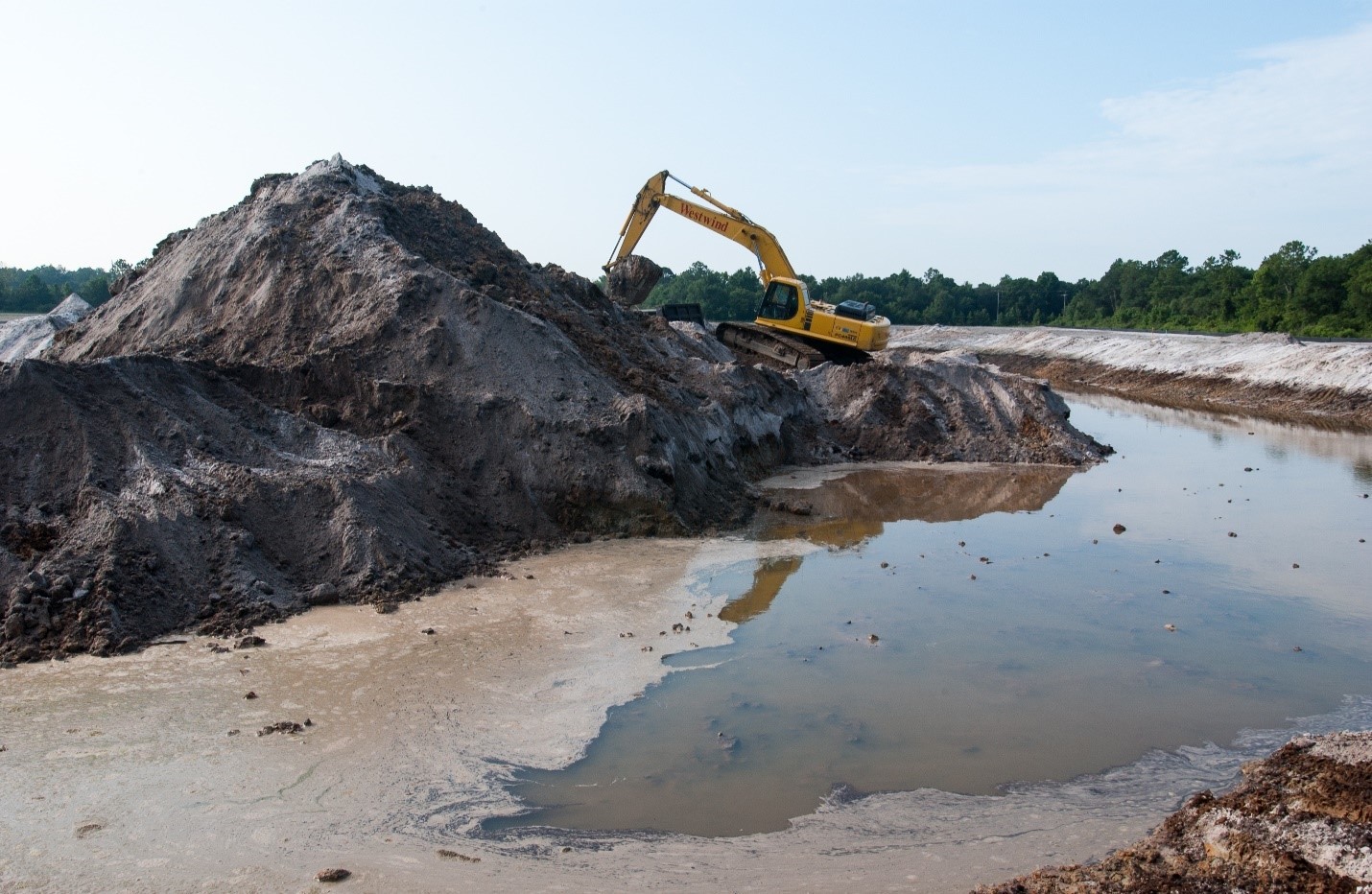 Excavator working on a large mound of dirt