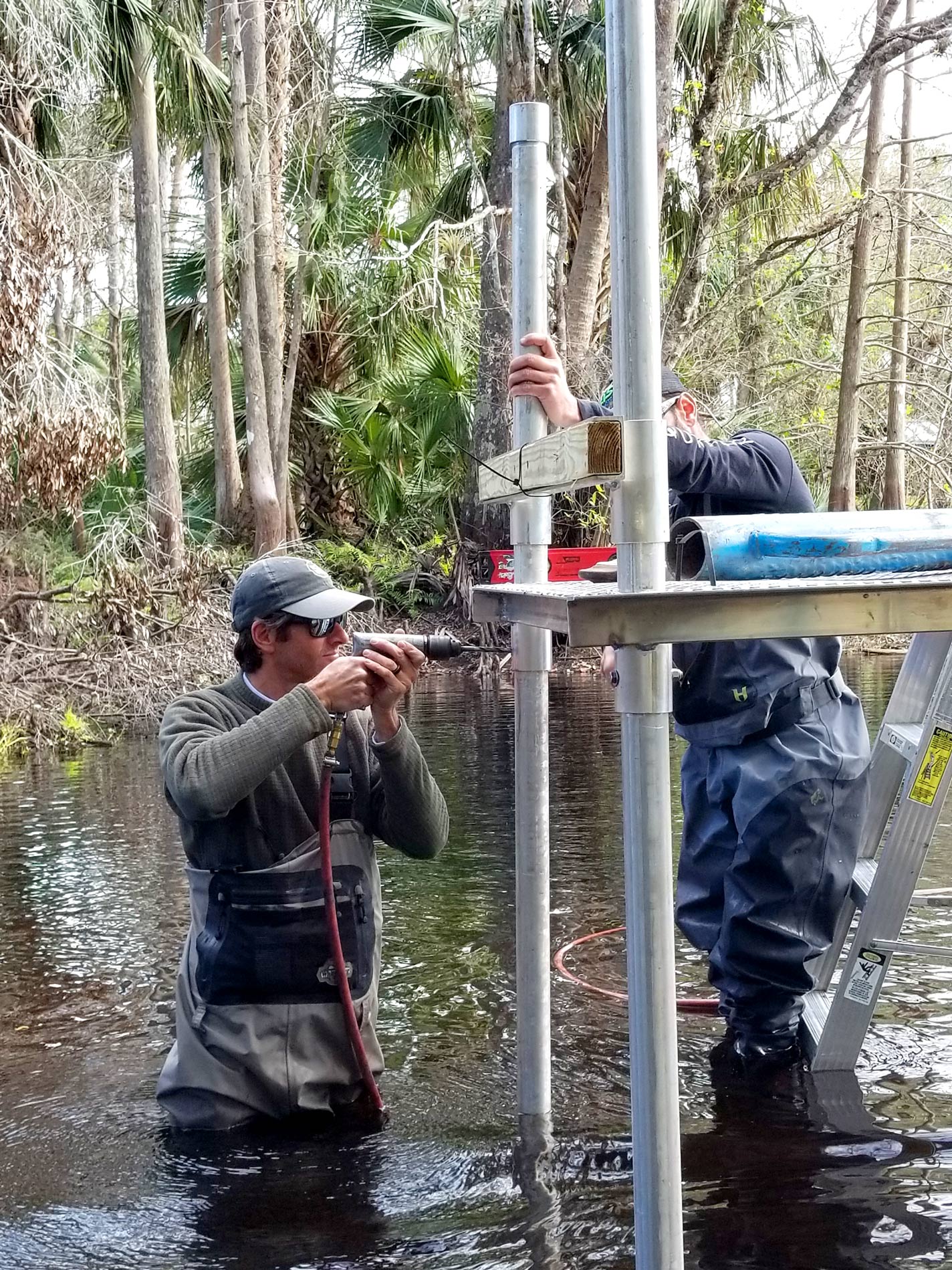 District staff installing a platform and monitoring equipment